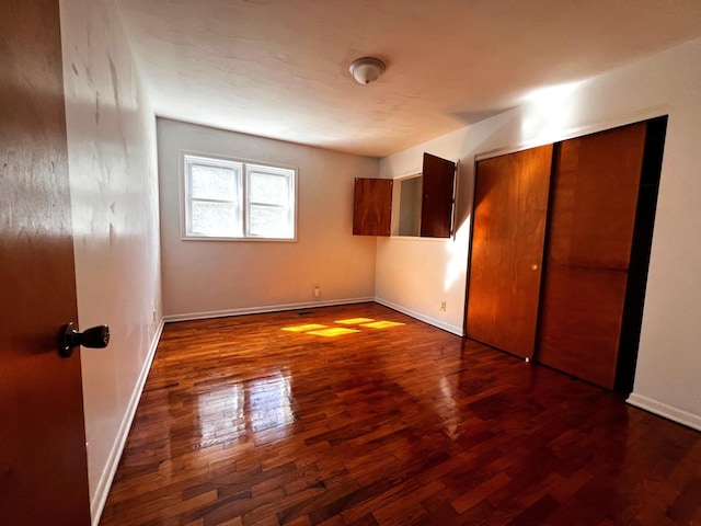 unfurnished bedroom featuring dark hardwood / wood-style floors and a closet