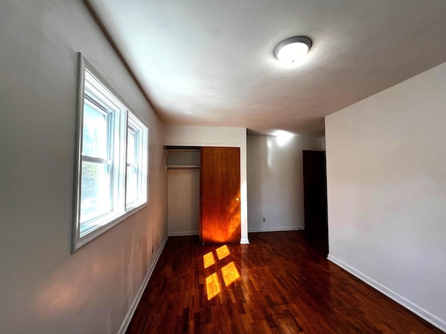 unfurnished bedroom with a closet and dark hardwood / wood-style flooring