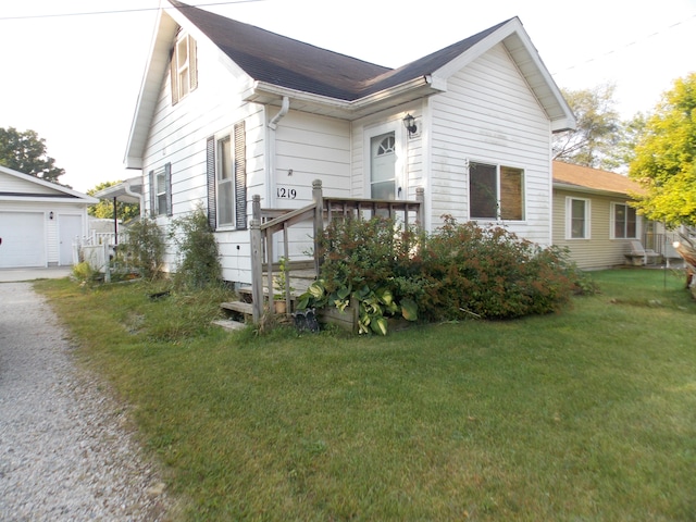 view of front of home featuring a garage, an outdoor structure, and a front yard