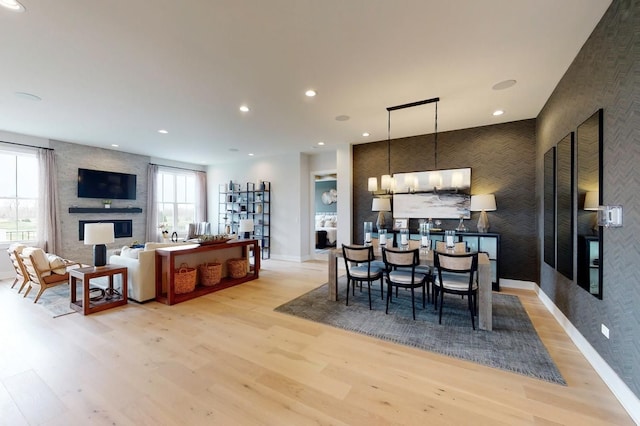 dining room with a chandelier, a fireplace, a wealth of natural light, and light hardwood / wood-style flooring