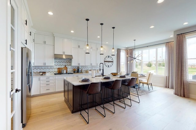 kitchen featuring white cabinetry, a kitchen island with sink, light hardwood / wood-style floors, and stainless steel appliances