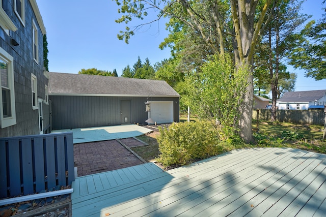 wooden terrace featuring an outbuilding, a patio, and a garage