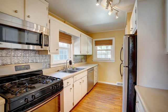 kitchen featuring appliances with stainless steel finishes, light hardwood / wood-style floors, white cabinetry, and sink