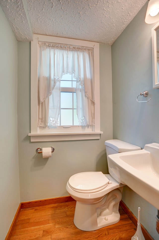 bathroom with a textured ceiling, hardwood / wood-style flooring, and toilet