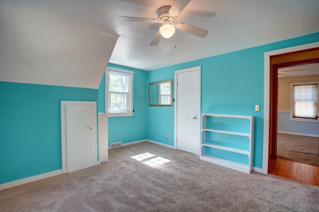 unfurnished bedroom featuring multiple windows, ceiling fan, and light carpet