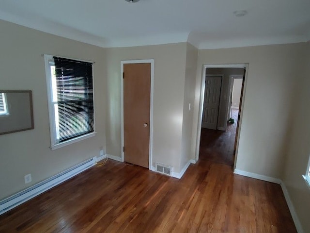 spare room with baseboard heating and dark wood-type flooring