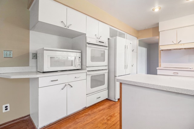 kitchen with white cabinets, light hardwood / wood-style floors, and white appliances