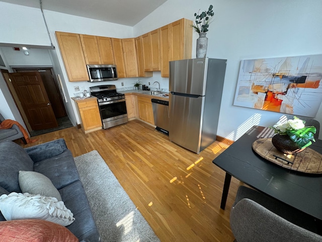 kitchen featuring light brown cabinets, sink, vaulted ceiling, appliances with stainless steel finishes, and light hardwood / wood-style floors