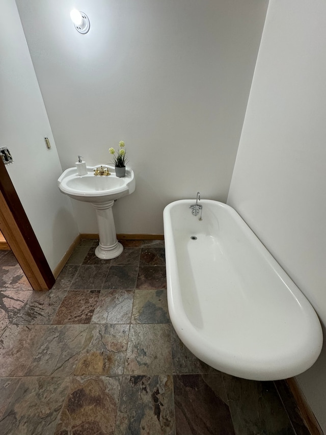 1395 Antietam Ave Unit 57, Detroit, MI 48207 - bathroom featuring stone tile floors, a soaking tub, and baseboards