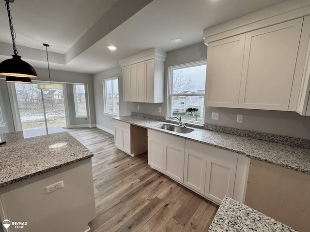 kitchen featuring white cabinets, light wood-type flooring, a wealth of natural light, and sink