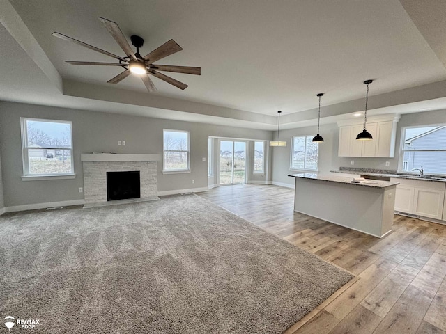 kitchen featuring sink, a center island, a tray ceiling, white cabinets, and decorative light fixtures