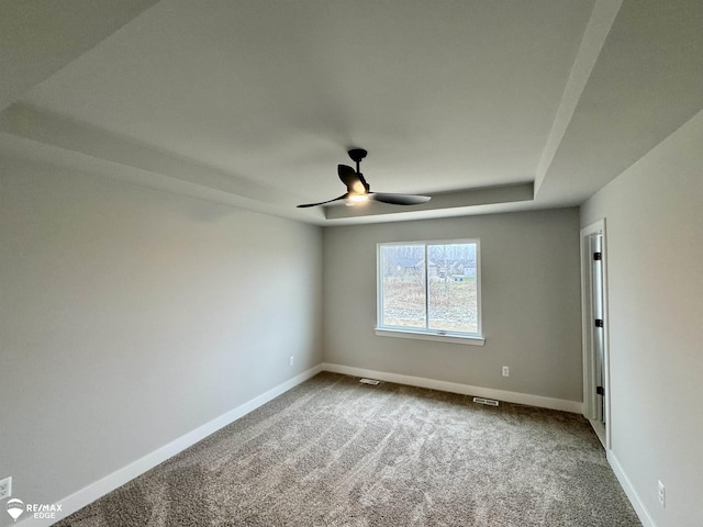 unfurnished room with carpet, ceiling fan, and a tray ceiling