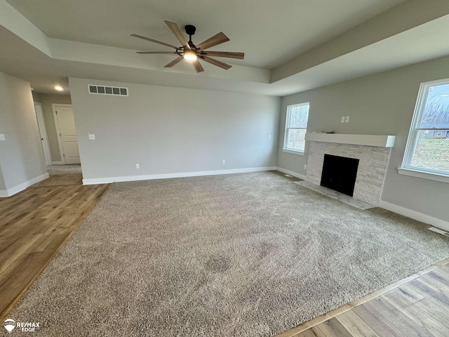 unfurnished living room with hardwood / wood-style flooring, ceiling fan, and a tray ceiling