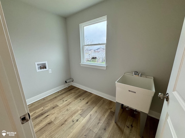 clothes washing area with sink, hookup for a washing machine, and light hardwood / wood-style flooring