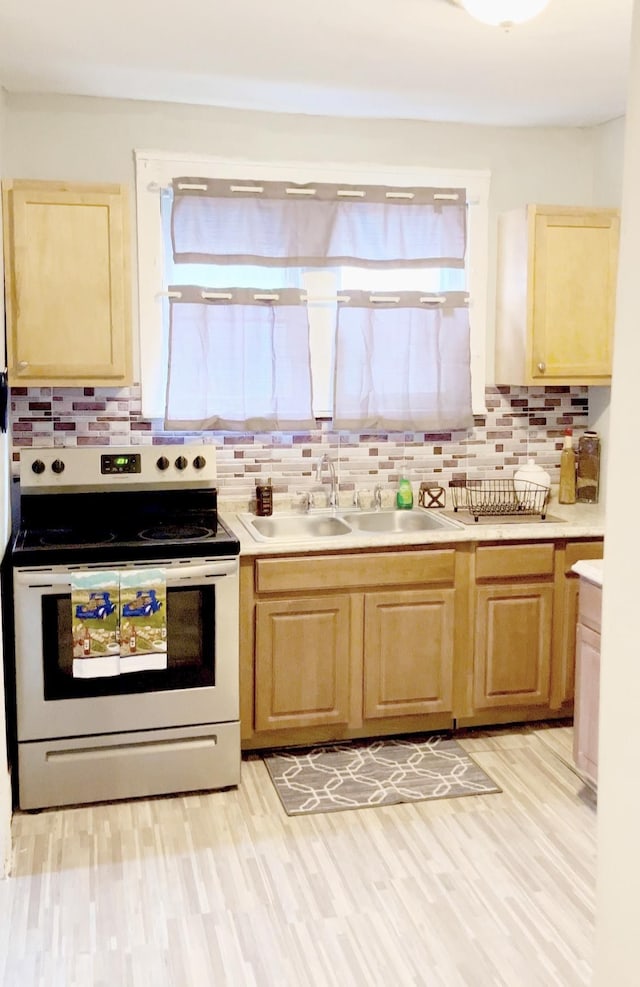 kitchen featuring backsplash, electric range, sink, and light hardwood / wood-style flooring