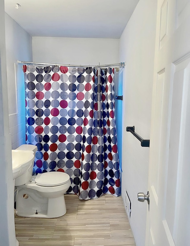 bathroom featuring hardwood / wood-style flooring, a shower with shower curtain, tile walls, and toilet