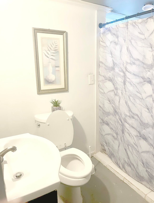 bathroom with concrete floors, toilet, curtained shower, and sink