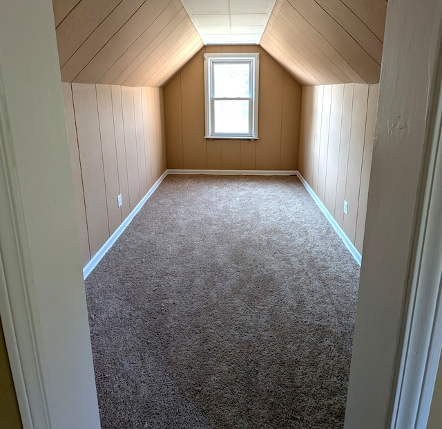 additional living space with carpet flooring, wooden walls, and vaulted ceiling