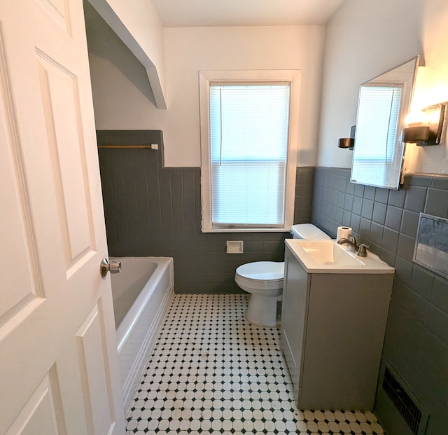 bathroom featuring vanity, a bathtub, toilet, and tile walls