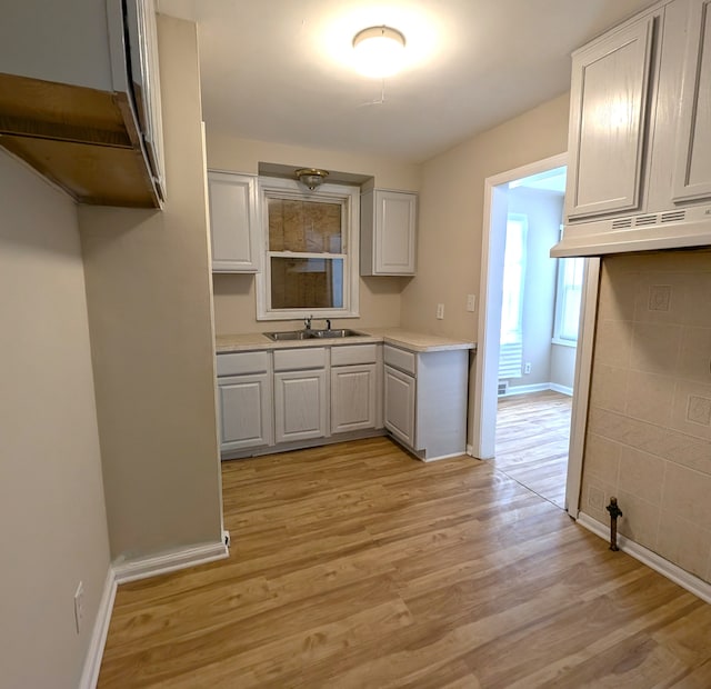 kitchen featuring white cabinets, light hardwood / wood-style flooring, and sink