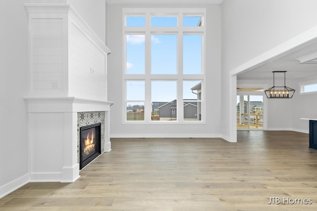 unfurnished living room with a tiled fireplace, plenty of natural light, and light hardwood / wood-style floors