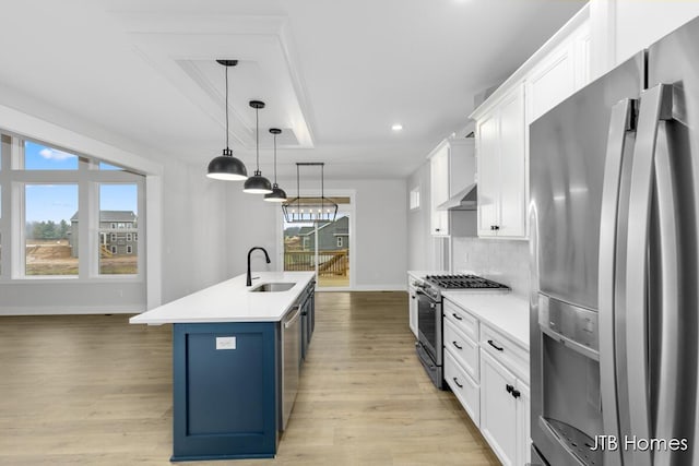 kitchen with sink, appliances with stainless steel finishes, a kitchen island with sink, white cabinetry, and decorative light fixtures