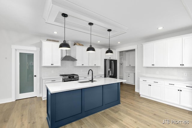 kitchen with pendant lighting, sink, white cabinetry, stainless steel appliances, and an island with sink