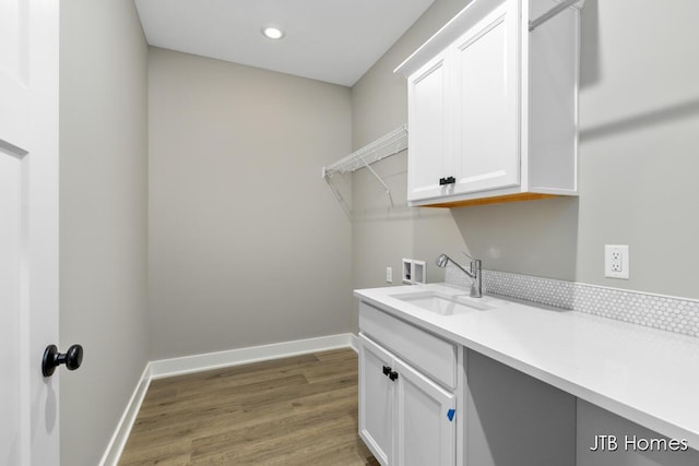 laundry area featuring hookup for a washing machine, sink, hardwood / wood-style floors, and cabinets