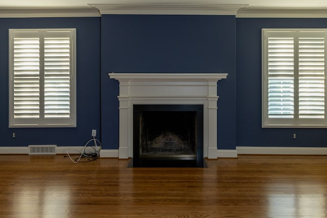 unfurnished living room featuring dark hardwood / wood-style floors and crown molding