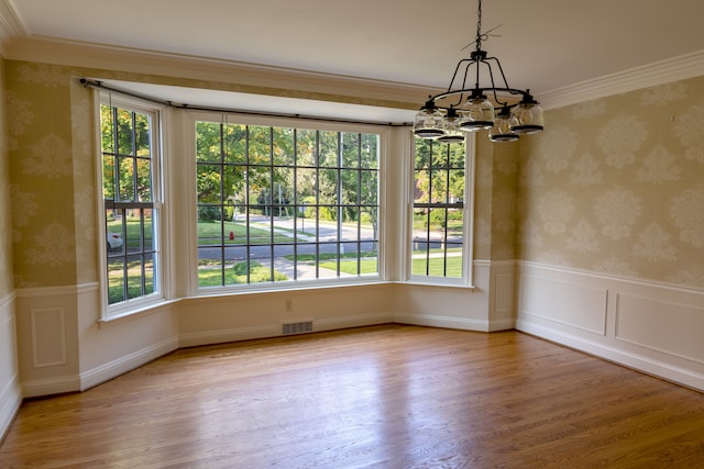 unfurnished dining area with a wealth of natural light, crown molding, and wood-type flooring