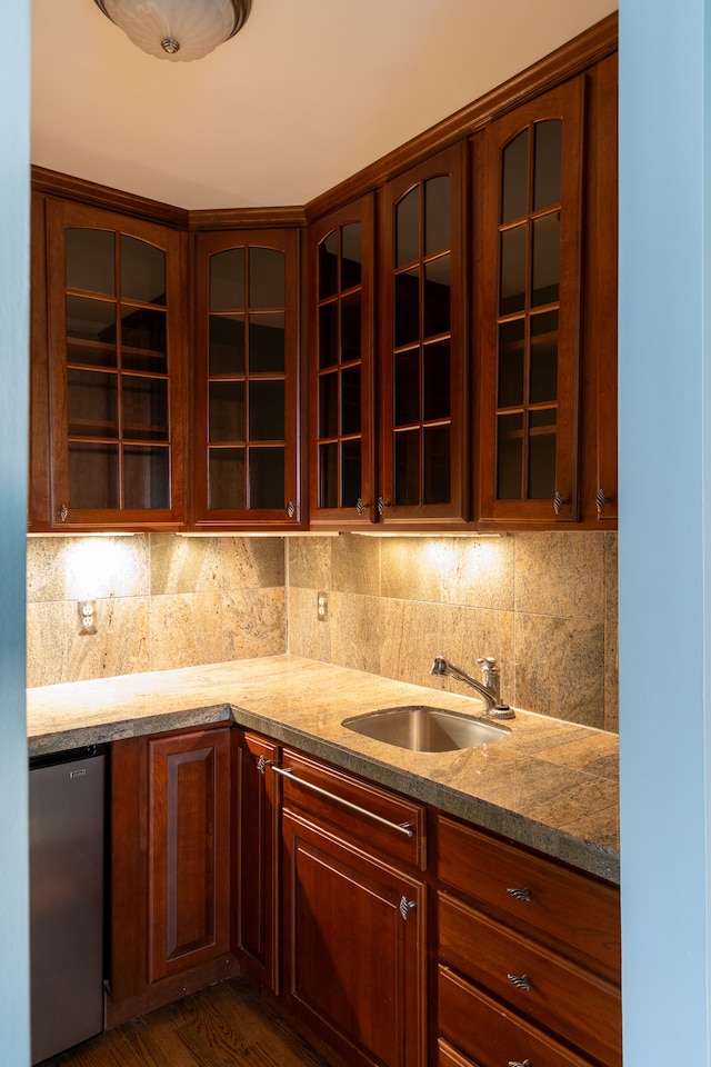 kitchen featuring decorative backsplash, stainless steel fridge, dark hardwood / wood-style flooring, light stone counters, and sink