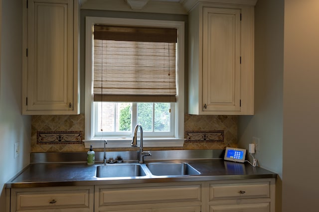 kitchen with cream cabinets, sink, and tasteful backsplash