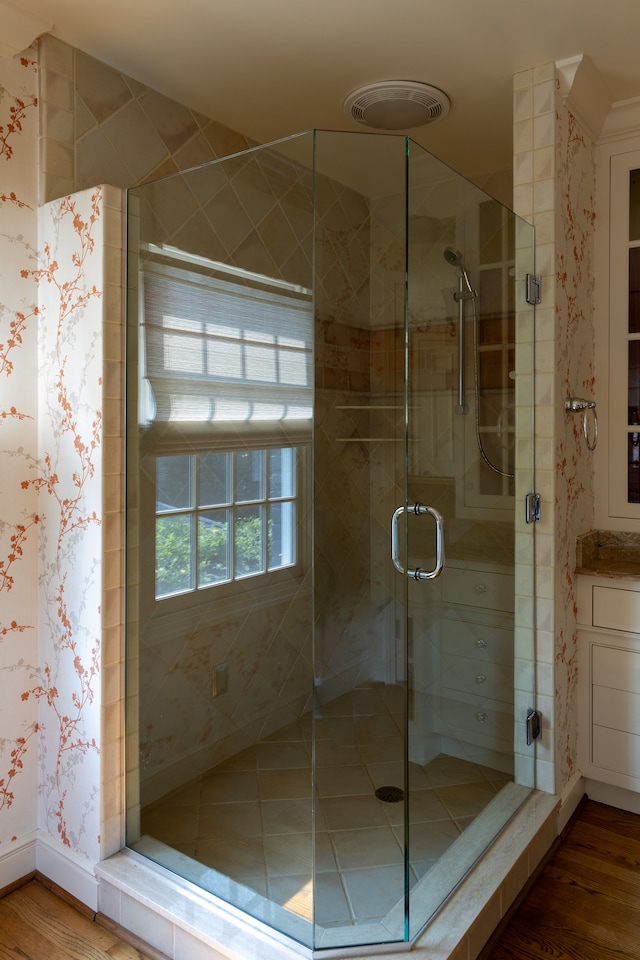 bathroom with hardwood / wood-style flooring and a shower with shower door