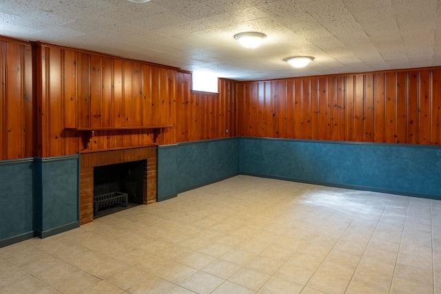 basement featuring wooden walls, a fireplace, and a textured ceiling