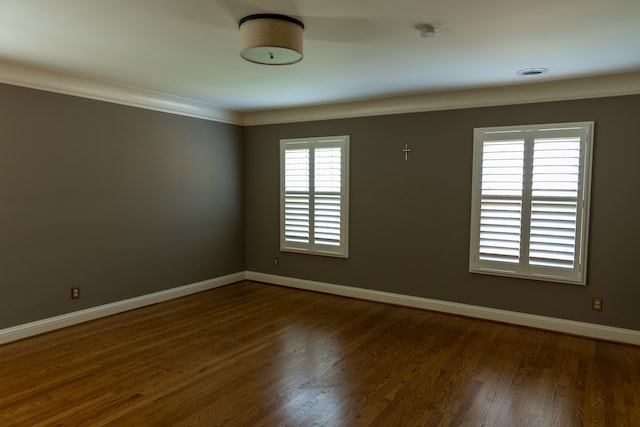 unfurnished room featuring dark hardwood / wood-style floors, ornamental molding, and a wealth of natural light