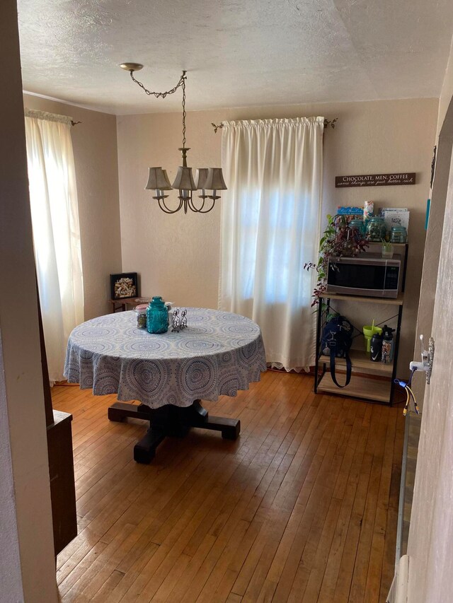 dining room featuring hardwood / wood-style flooring, a textured ceiling, and a chandelier