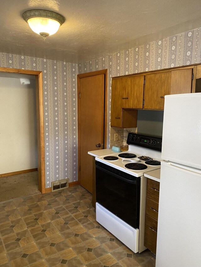 96 Harold St, Grant, MI 49327 - kitchen with freestanding refrigerator, range with electric cooktop, wallpapered walls, light countertops, and brown cabinets