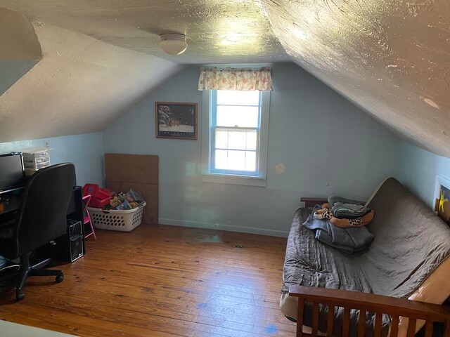 home office with a textured ceiling, hardwood / wood-style flooring, and vaulted ceiling