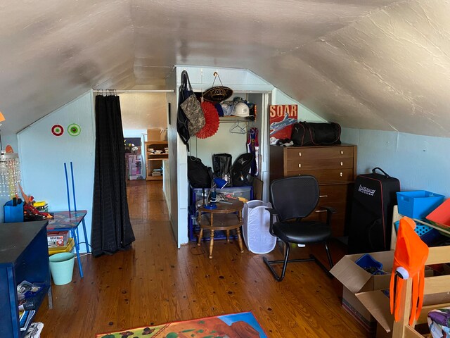 additional living space with hardwood / wood-style floors and vaulted ceiling