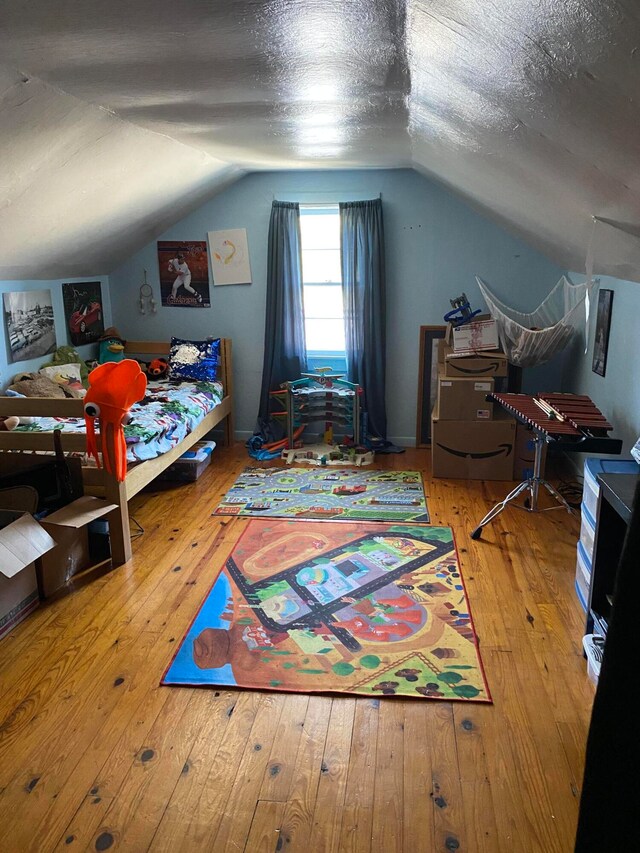 bedroom with a textured ceiling, lofted ceiling, and hardwood / wood-style flooring