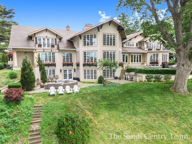 rear view of property with an outdoor living space, a patio, french doors, and a lawn