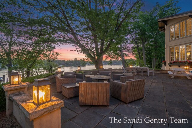 18635 N Fruitport Rd, Spring Lake, MI 49456 - patio terrace at dusk featuring a patio area, an outdoor living space with a fire pit, and a water view