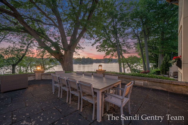 patio terrace at dusk featuring a water view