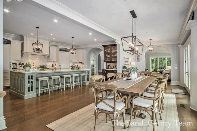 18635 N Fruitport Rd, Spring Lake, MI 49456 - dining area with arched walkways, dark wood-style flooring, recessed lighting, ornamental molding, and a chandelier