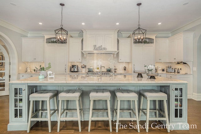 kitchen featuring a large island with sink, white cabinetry, hanging light fixtures, and a kitchen breakfast bar