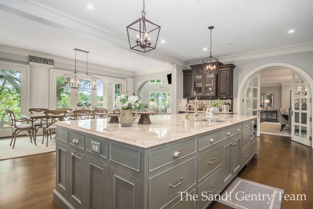 kitchen with dark brown cabinetry, a kitchen island with sink, ornamental molding, and sink