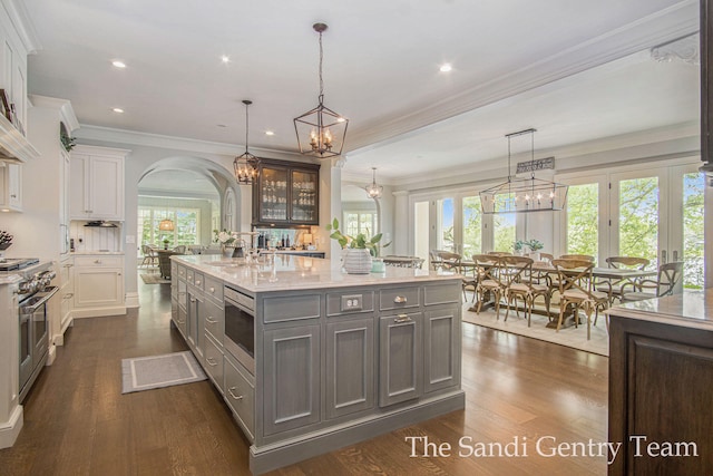 kitchen featuring white cabinets, pendant lighting, a center island with sink, and dark wood-type flooring