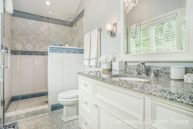 bathroom with tile patterned floors, vanity, vaulted ceiling, tiled shower, and toilet