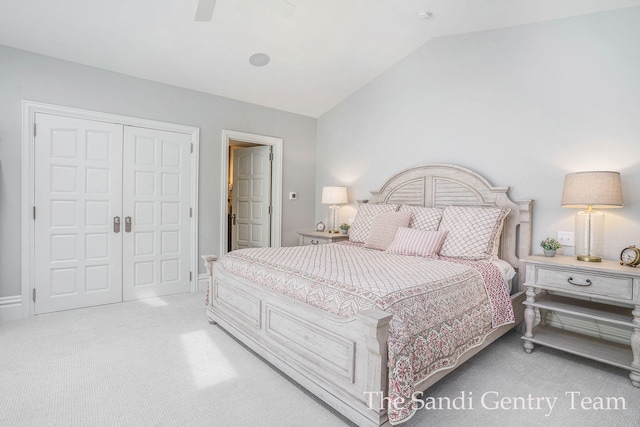 bedroom with ceiling fan, a closet, light carpet, and vaulted ceiling