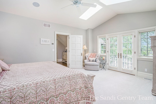 carpeted bedroom featuring french doors, access to outside, lofted ceiling with skylight, and ceiling fan